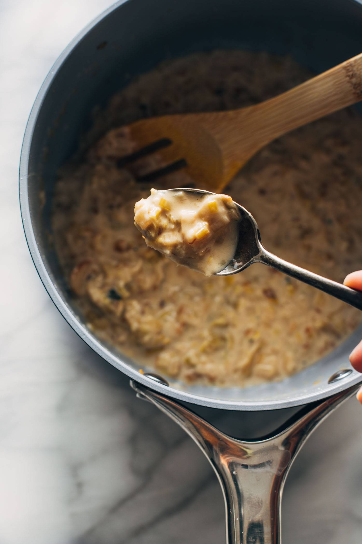 Creamed leek sauce on a spoon over a saucepan