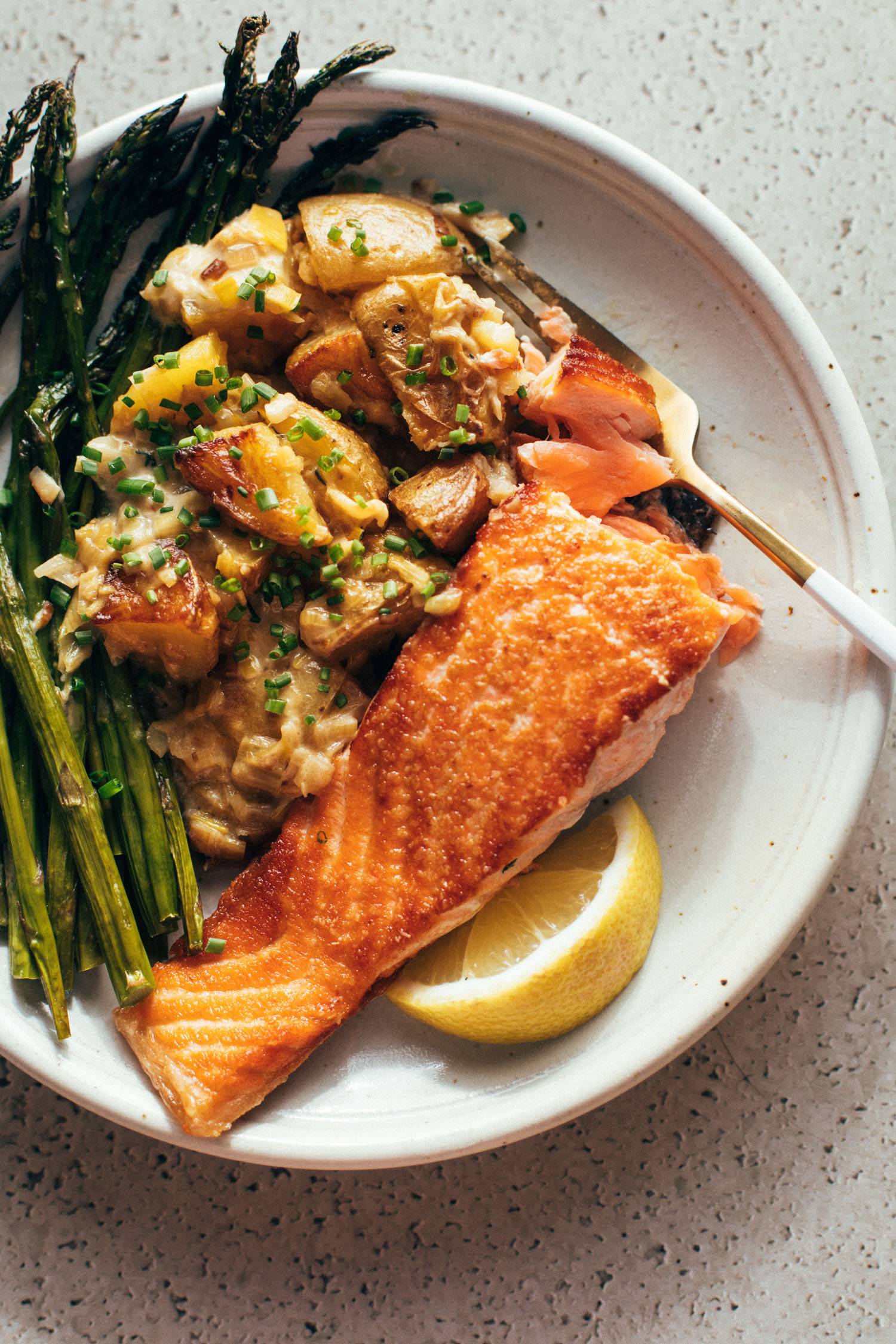 Pan-fried salmon on a plate with asparagus, potatoes, and creamed leeks